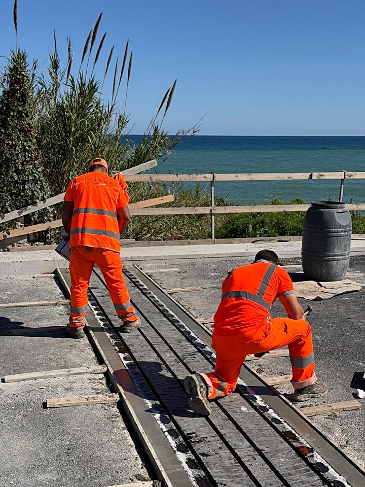 Due operai Canale Costruzioni posano un giunto di dilatazione su un ponte vicino al mare